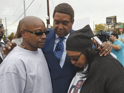 Attorney John Burris, center, comforts Robert and Deborah Mann, family members of Joseph Mann, who was killed by Sacramento Police in July, after a news conference Monday, Oct. 3, 2016, in Sacramento, Calif. 